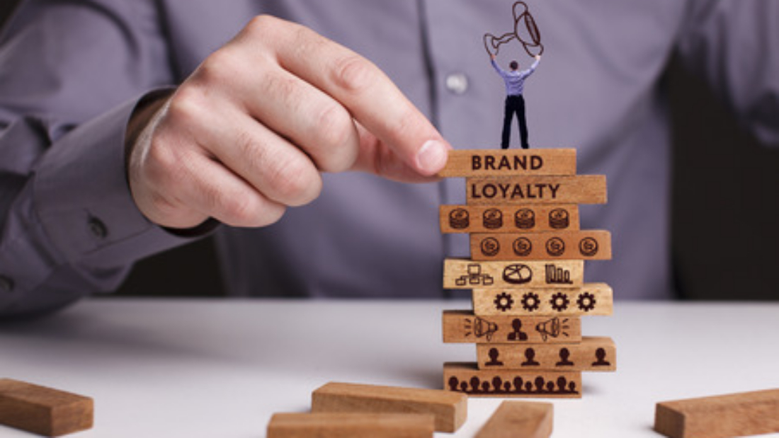 Man Standing on Block Tower that Says Brand Loyalty