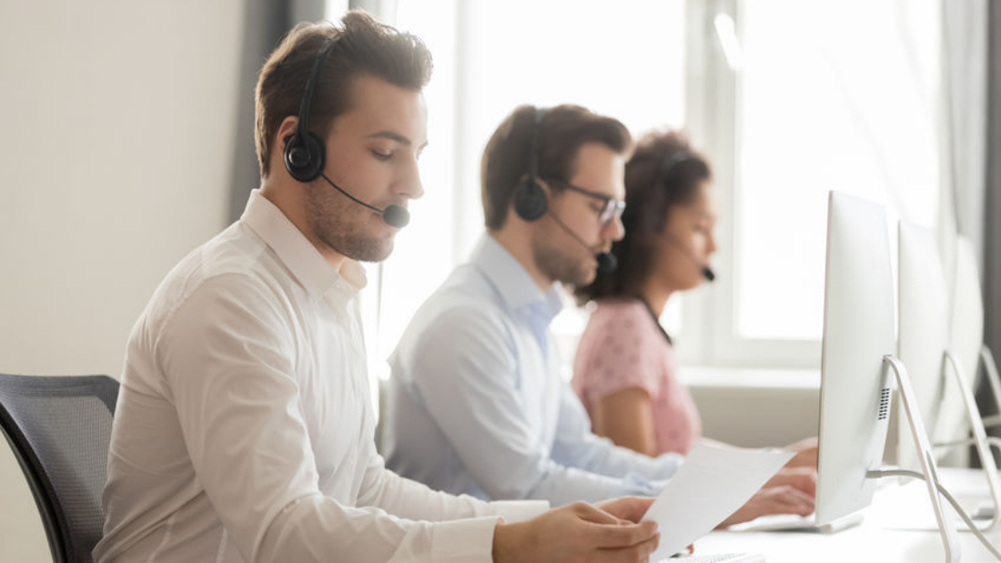 Service phone operators sitting at workplaces communicating with customers distantly