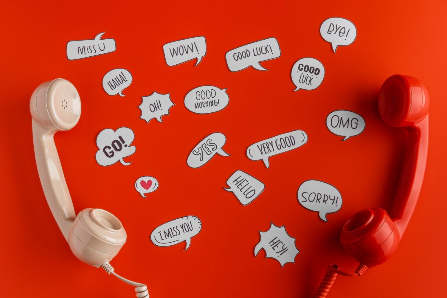 A creative visual representation of communication featuring a red and a beige vintage telephone handset on a vibrant red background. Surrounding the handsets are multiple white speech bubbles with various messages like "Hello," "Good Luck," "OMG," and "Miss U," symbolizing conversation and connectivity. 