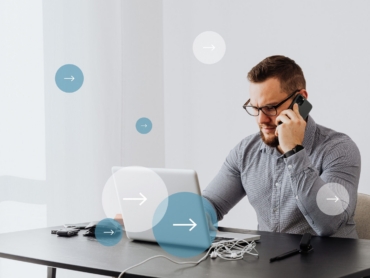 Professional man multitasks with laptop and smartphone in home office environment.