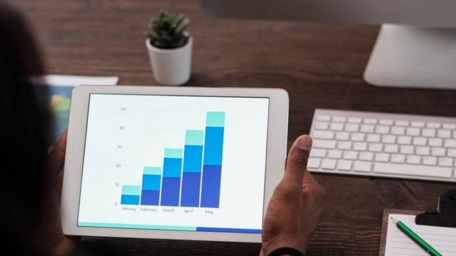 A person reviews statistical graphs on a tablet, showcasing data analysis and technology.