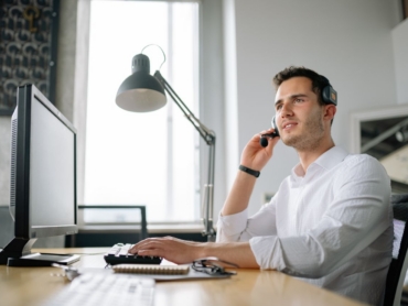 Male call center agent with headset working at desk, providing excellent customer service.