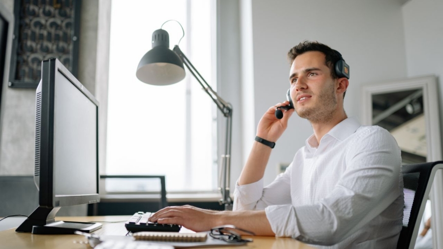 Male call center agent with headset working at desk, providing excellent customer service.