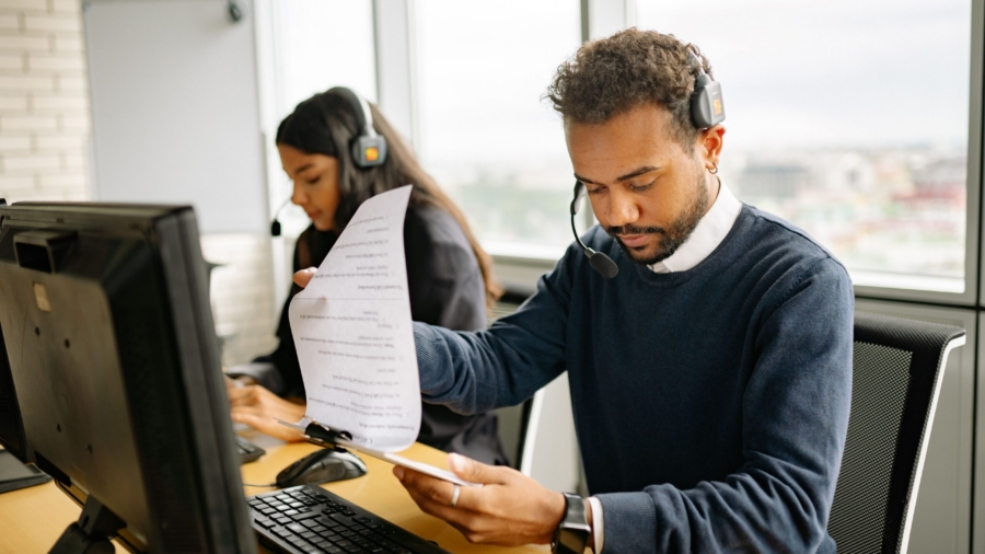 Call center agents with headsets working in a modern office setting, reviewing documents.